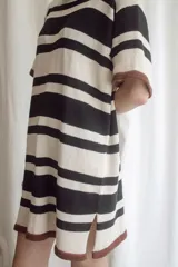 Vestido corto tejido a rayas horizontales negras y crudas, con cuello redondo, mangas cortas y aberturas laterales en el ruedo. Tejido artesanal en hilado 70% algodón y 30% acrílico.