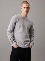 Remera gris de punto gofrado, corte slim, cuello redondo, mangas largas y puños de canalé.