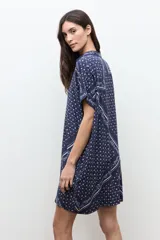 Vestido túnica azul marino con estampado paisley y floral blanco, de corte recto, manga corta y cierre frontal con botones.