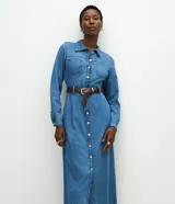 Vestido midi de denim con cuello camisero, mangas largas con puños abotonados y cierre frontal completo con botones metálicos. Presenta bolsillos frontales en el busto y un corte recto estructurado.