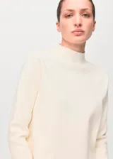 Sweater de punto fino color blanco marfil, de corte recto, con cuello perkins y manga larga.