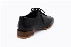 Zapatos acordonados de cuero color negro, con diseño de punta cuadrada, costuras centrales decorativas y suela marrón con taco bajo.