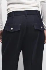 Pantalón de tiro alto con pernera recta, confeccionado en denim oscuro. Presenta nervios marcados en el delantero, bolsillos frontales tipo parche y cierre frontal con cremallera y botón.