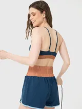 Top deportivo azul denim de sujeción media y corte ajustado, con tirantes finos y detalle bicolor en la banda inferior. Confeccionado con tecnología Aloe Vera.