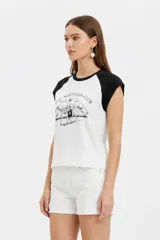 Remera al cuerpo con diseño raglán, color blanco en el torso y azul marino en las mangas cortas y el cuello. Cuenta con un estampado frontal de temática de tenis con las inscripciones "Portofino Tennis" y "Summer Italia".