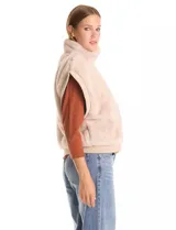 Chaleco de piel sintética en color beige, con cuello alto, cierre frontal metálico y terminaciones en tejido rib en el ruedo y sisas.