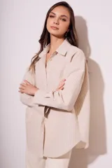 Camisa oversize color arena con rayas verticales marrones, de manga larga y cuello clásico.