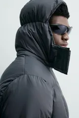 Cazadora acolchada tipo puffer de corte regular, confeccionada en tejido técnico repelente al agua. Cuenta con cuello subido, capucha ajustable y desmontable, cierre frontal con cremallera, bolsillos laterales con cremallera oculta y puños ajustables con tira adherente.
