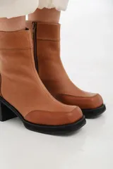 Botas negras de cuero con caña corta, punta cuadrada y cierre lateral con cremallera.