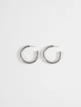 Aros tipo argolla de diseño curvo y minimalista, fabricados en acero quirúrgico hipoalergénico con acabado plateado.