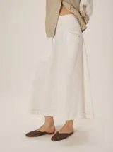 Falda midi blanca de lino y tencel, con bolsillos laterales y costuras pespunteadas en contraste.