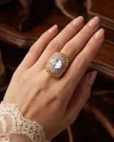 Anillo grande de bronce con baño de oro, diseño texturizado en forma de flor con incrustaciones de circón pavé y una piedra central ovalada transparente.