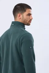 Buzo de abrigo confeccionado en tejido polar térmico, con cuello alto y cierre frontal parcial con broches. Presenta bolsillos laterales con cierre y un bolsillo adicional con cierre en la manga izquierda.