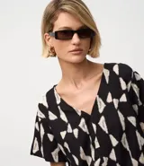 Blusa de manga corta con escote en V y un estampado geométrico abstracto en blanco y negro.