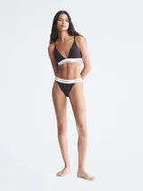 Brasier tipo triángulo con copas forradas y relleno, confeccionado en tejido de algodón modal. Presenta tirantes finos ajustables y una banda elástica inferior distintiva con el logo de Calvin Klein.