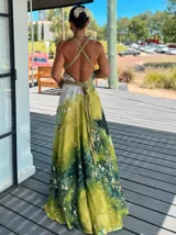 Vestido largo verde con diseño estampado tipo tie-dye y detalles dorados, de corte fluido, un solo hombro y diseño amplio.