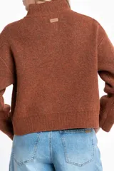 Cardigan de lana color marrón, con cuello alto, cierre frontal de botones y dos bolsillos delanteros. Presenta puños y ruedo acanalados.