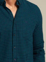 Camisa celeste a cuadros con cuello abotonado, manga larga y bolsillo en el pecho.