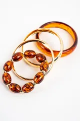 Set de pulseras compuesto por cuatro piezas de diseño combinado: una pulsera rígida carey en tonos marrones, dos pulseras rígidas metálicas doradas y una pulsera elástica de cuentas ovaladas símil carey con detalles dorados.