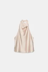 Top de cuello halter con escote fluido y caída suave. Presenta cierre con botones en la parte posterior y diseño sin mangas.