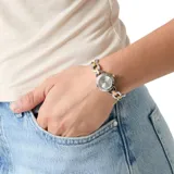 Reloj analógico Guess modelo Siren con caja y malla de acero inoxidable en tono bicolor plateado y dorado. Presenta esfera plateada con acabado sunray, bisel con grabado de la marca y detalles de cristales.