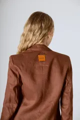 Blazer color crema con solapas de muesca, cierre frontal con dos botones y mangas largas con puños abotonados.