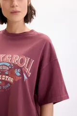 Camiseta boxy de manga corta color bordó con estampa frontal inspirada en el rock con leyendas "Rock & Roll" y "Rock Star World Tour".