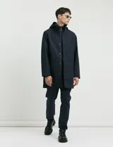 Gabardina con capucha de corte recto y largo medio. Cuenta con cierre frontal engomado, cartera con botones a presión, bolsillos laterales y tejido repelente al agua y al viento.