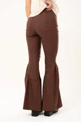 Pantalón de corte ajustado en la parte superior y pierna acampanada con volados en el ruedo. Presenta cierre frontal y bolsillos laterales.