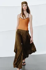 Pantalón de tiro medio confeccionado en viscosa, con diseño de pierna ancha y drapeado lateral. Presenta cintura con trabillas y cierre de cremallera oculto en la costura.