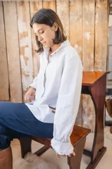 Camisa de manga larga con rayas finas, cuello mao con volados y cierre frontal de botones.
