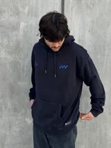 Canguro negro con capucha ajustable con cordones, bolsillo tipo canguro y logo bordado en azul en el pecho.