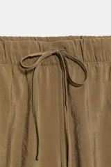 Pantalón fluido confeccionado en mezcla de modal, de tiro medio con cintura elástica ajustable con cordón y bolsillos laterales, en color tostado.