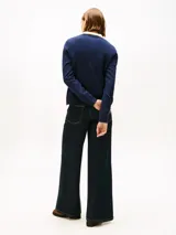 Cárdigan de punto azul marino con cuello en V, cierre frontal con botones dorados y bolsillos delanteros con ribetes en contraste. Presenta detalles en lurex en el cuello y los bolsillos, y logo de la marca bordado en el pecho.