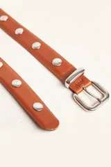 Cinto de cuero color suela con tachas metálicas circulares y hebilla plateada.