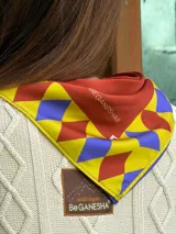 Pañuelo cuadrado de seda con diseño estampado en tonos naranja, azul, amarillo y blanco, con logo de la marca.