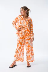 Pantalón palazzo naranja con estampado de hojas blancas, cintura elástica y corte amplio.