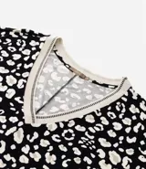 Blusa de crepé con estampa de manchas en blanco y negro, mangas cortas y escote en pico con borde contrastante.