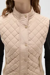 Chaleco negro con diseño capitoneado, cierre frontal con botones a presión y cuello alto.