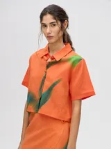 Camisa crop de manga corta con cuello camisero y cierre frontal de botones. Confeccionada en viscosa con un estampado abstracto único en tonos marrones y rosados.