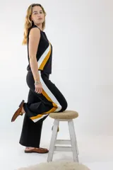 Pantalón negro de corte palazzo con rayas laterales blancas y mostaza.