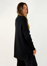 Sweater de punto color beige, de corte holgado y diseño oversize. Presenta cuello alto y puños con detalle de tejido trenzado, al igual que en el ruedo inferior.