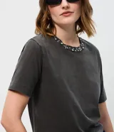 Remera de algodón con efecto de lavado desgastado, cuello redondo acanalado con aplicación de brillos y manga corta.