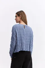Blusa de manga larga con textura fruncida en toda la prenda, cuello redondo y corte relajado.