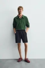 Polo de manga larga con cuello solapa y cierre frontal de botones. Presenta un tejido jacquard texturizado con rayas horizontales en tonos de verde.
