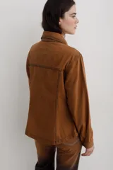 Chaqueta de denim color marrón, con corte entallado en la cintura, cierre frontal con botones metálicos y bolsillos superiores con solapa.