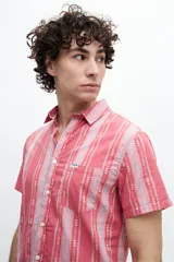 Camisa manga corta a rayas verticales rojas y grises, confeccionada en tela 100% algodón. Tiene bolsillo en el pecho, botones personalizados y calce clásico.