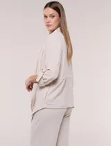 Chaqueta liviana color beige de silueta fluida y diseño abierto, con solapa caída, cintura con cordón ajustable y mangas 3/4 con presilla y argolla metálica.