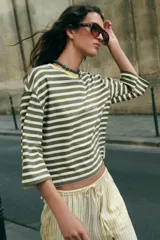 Camiseta de algodón a rayas horizontales en tonos marrones y beige, de corte regular fit, cuello redondo a contraste de color marrón oscuro y mangas largas por debajo del codo. Presenta diseño de bajo asimétrico.