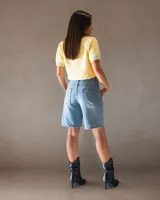 Bermuda de denim celeste con lavado suave, de calce relajado y tiro medio. Presenta diseño de cinco bolsillos y cierre frontal con botón y cremallera.